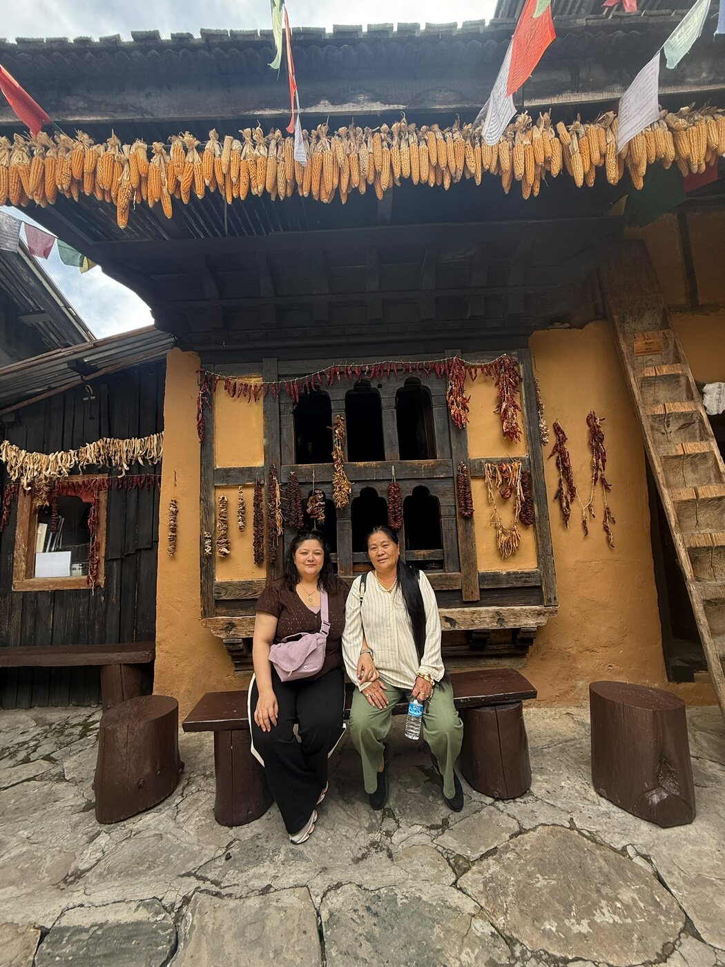 Visitors in a traditional Bhutanese courtyard decorated with drying corn and chillies