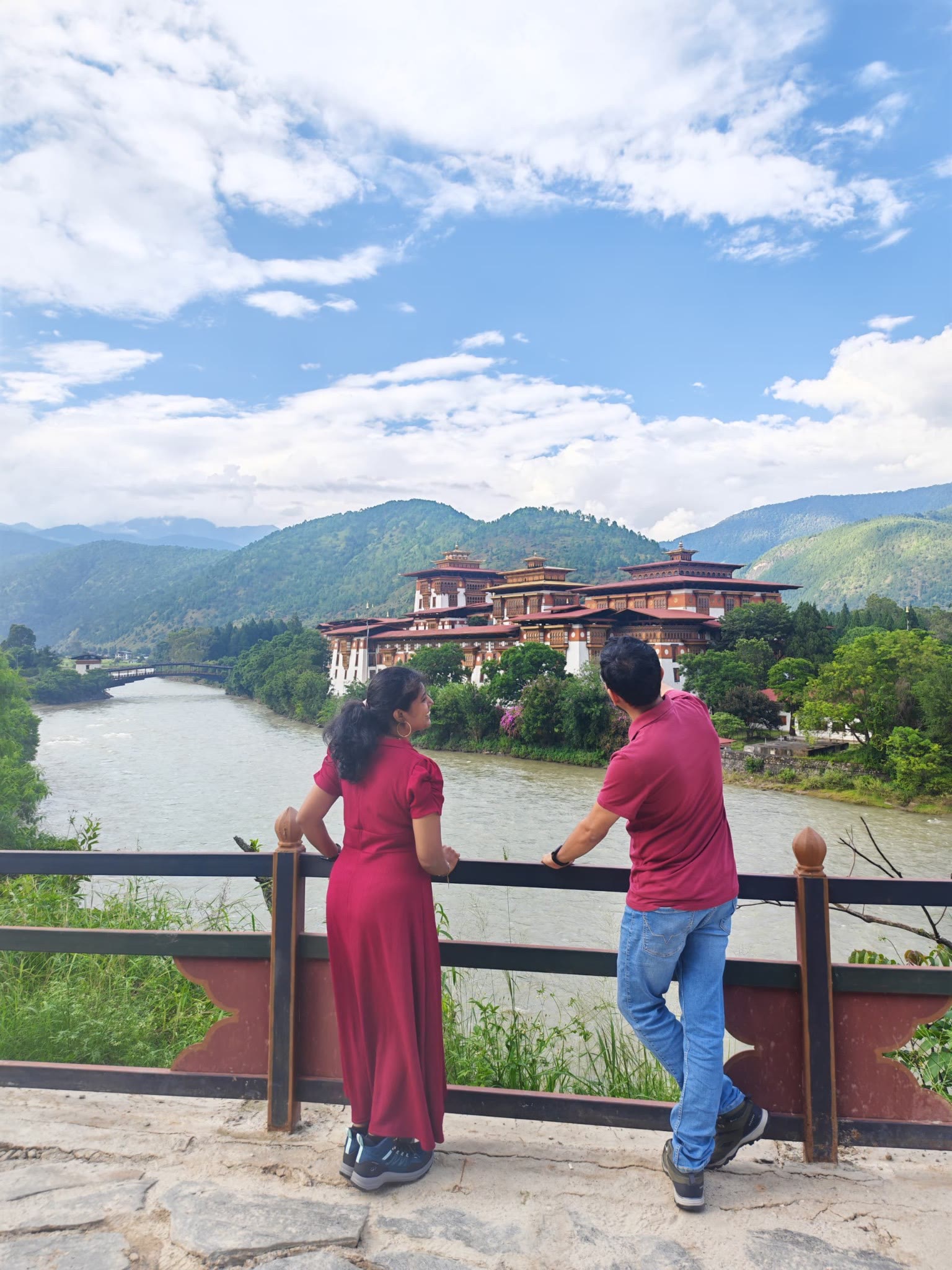 Two travellers overlooking Punakha Dzong beside the river